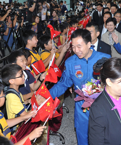 在太空任指令長的景海鵬與夾道歡迎的小朋友握手。