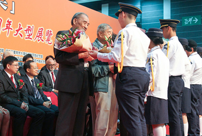 Former resistance fighters of the Hong Kong Independent Battalion of the Dongjiang Column being presented with flowers by Hong Kong youth representative